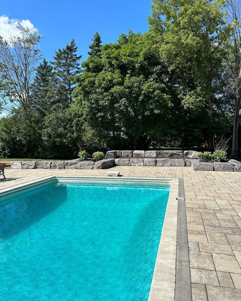 Tiered armour stone walls and raised gardens around a pool, Nobleton. Thor Construction job photo.