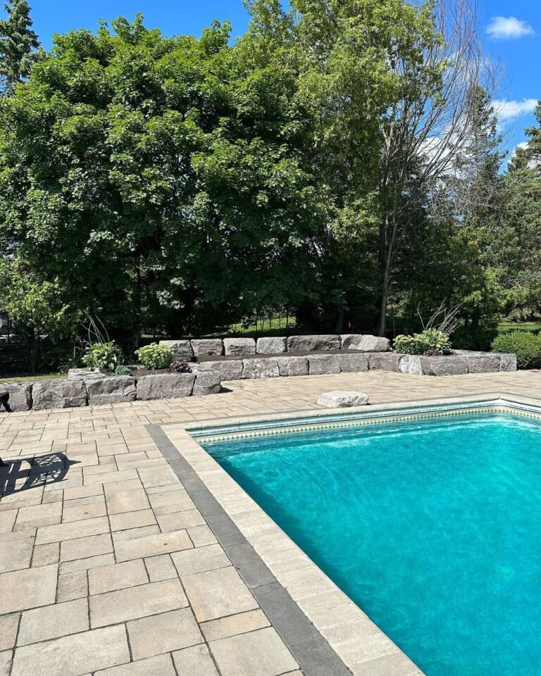 Tiered armour stone walls and raised gardens around a pool, Nobleton. Thor Construction job photo.