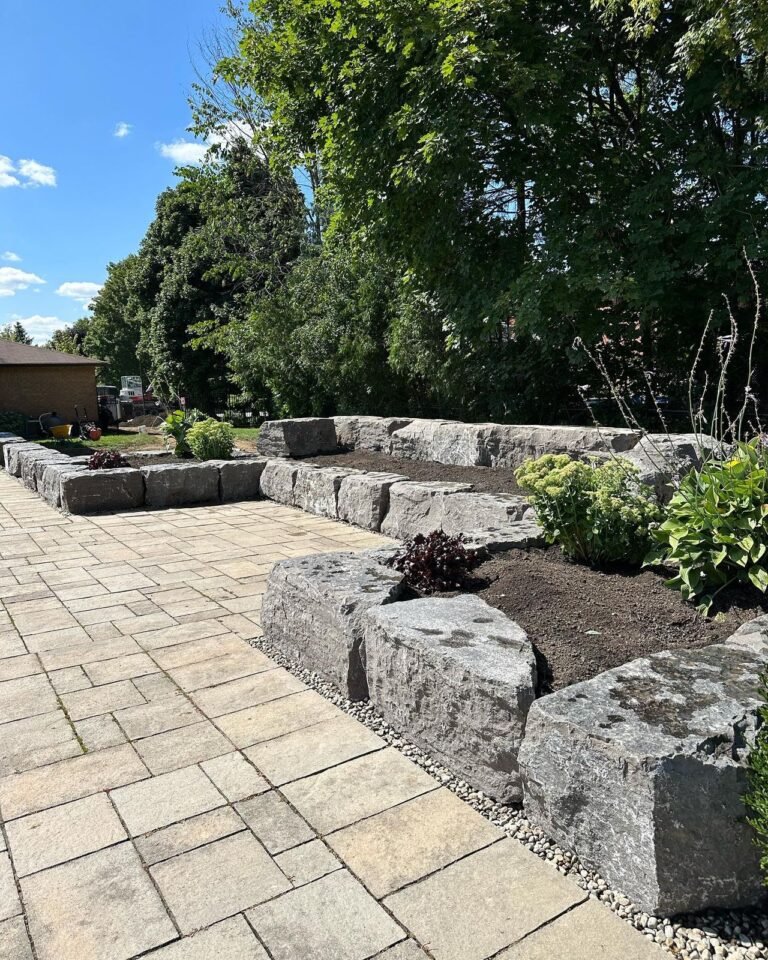 Tiered armour stone walls and raised gardens around a pool, Nobleton. Thor Construction job photo.