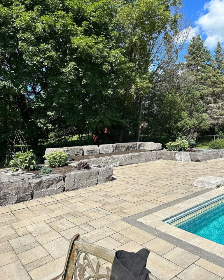 Tiered armour stone walls and raised gardens around a pool, Nobleton. Thor Construction job photo.