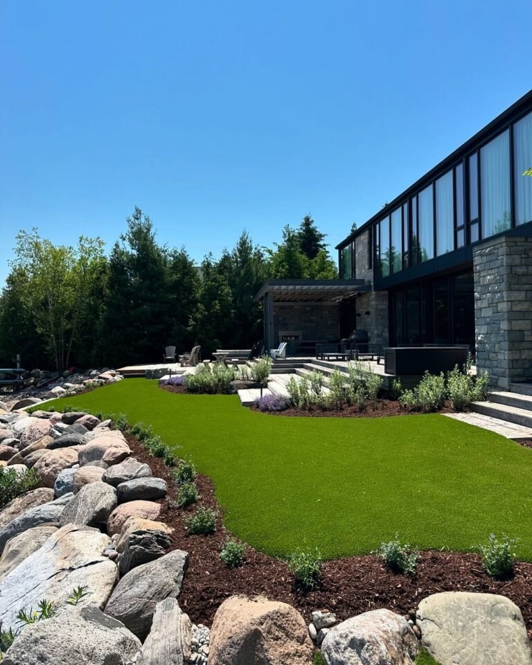 Finished landscape: sod, boulders and a stone patio. Thor Construction job photo.