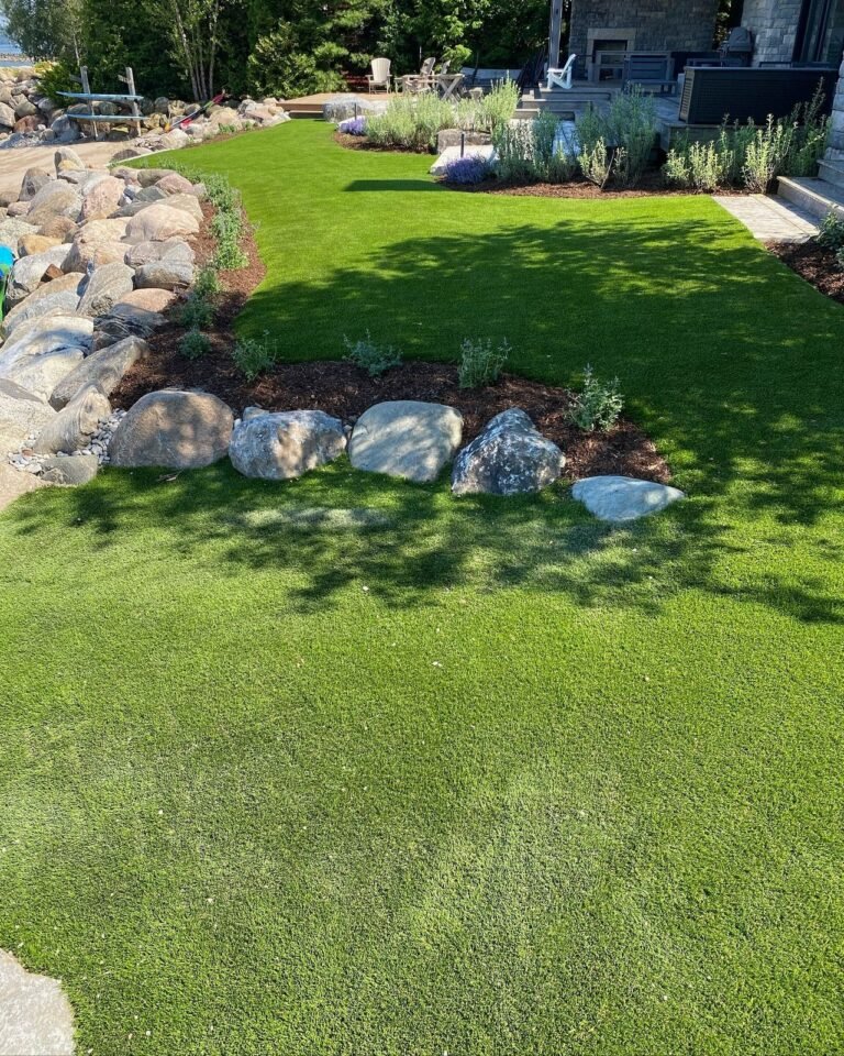 Finished landscape: sod, boulders and a stone patio. Thor Construction job photo.